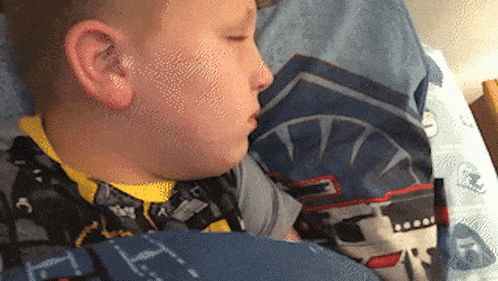 a young boy is sleeping in a bed with a blanket that has the letter t. on it