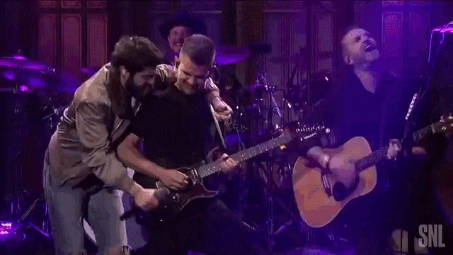 a man is holding another man 's arm while he plays a guitar .
