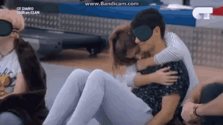 a man is carrying a woman on his back while wearing a blindfold .