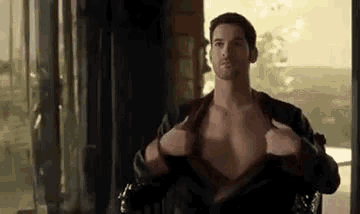 a shirtless man is sitting in a chair taking off his shirt .