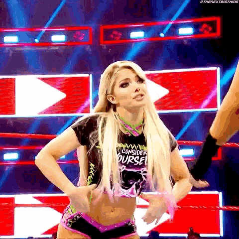 a woman is standing in a wrestling ring wearing a shirt that says " consider yourself "