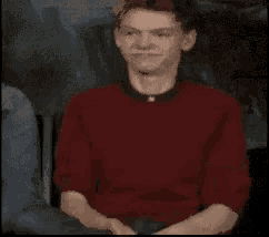 a close up of a man 's face with a red shirt and black collar