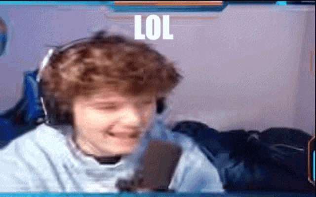 a young boy wearing headphones is laughing in front of a microphone and the word lol is on the screen .