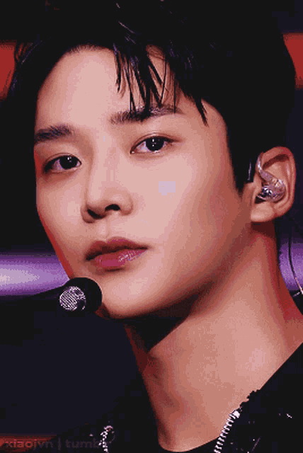 a close up of a young man 's face with a microphone in front of him and the words xiaoivn tumblr below him