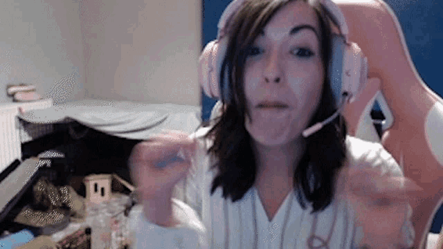 a woman wearing pink headphones is sitting in a pink chair and making a funny face .