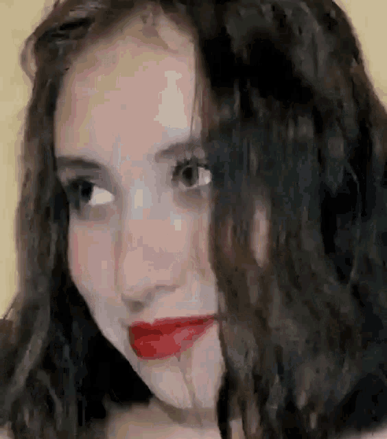 a close up of a woman with curly hair and red lipstick .