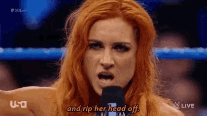 a woman with red hair is talking into a microphone and saying `` and rip her head off . ''