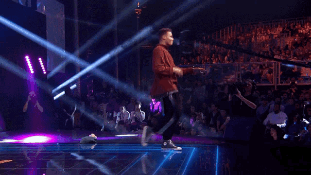 a man in a red jacket is dancing on stage