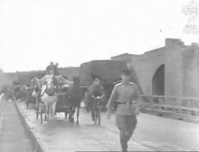 a black and white photo of a horse drawn carriage carrying soldiers .