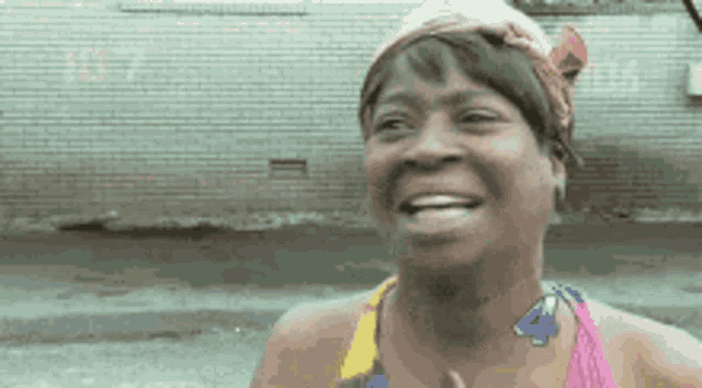 a woman wearing a pink tank top and a headband is smiling .