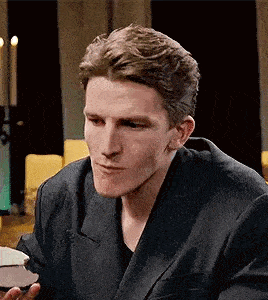 a man in a suit is sitting at a table holding a plate of food .