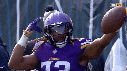a vikings player wearing a helmet and gloves holds a football