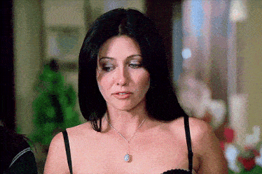 a woman in a black bra and necklace looks down