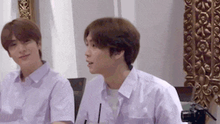 two young men in purple shirts are sitting next to each other in front of a mirror .
