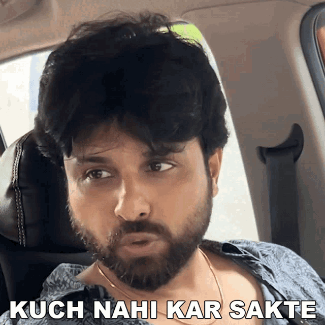 a man with a beard is sitting in the back seat of a car with kuch nahi kar sakte written above him