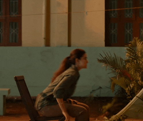 a woman squatting down in front of a building at night