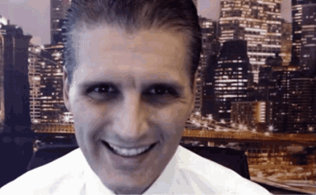 a man in a white shirt is smiling with a city skyline in the background