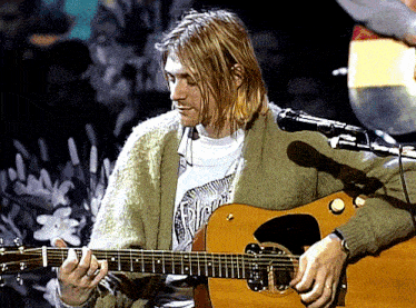 a man playing a guitar with a shirt that says ' nirvana ' on it