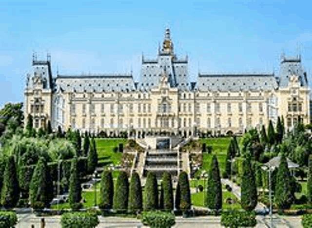 a large white building with a fountain in front of it is surrounded by trees and grass .
