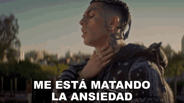 a man with a tattoo on his face and the words me esta matando la ansiedad on the bottom