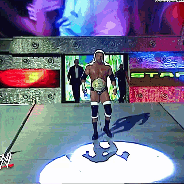 a wrestler is standing on a stage in front of a sign that says staf