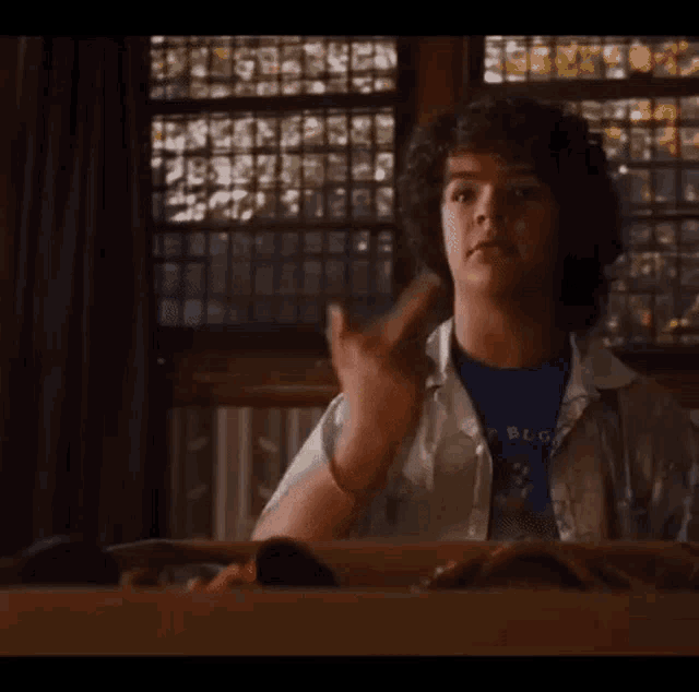 a young boy with curly hair is giving the middle finger .