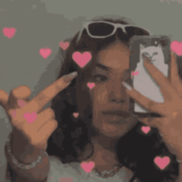 a woman wearing sunglasses is taking a picture of herself with her tongue out .