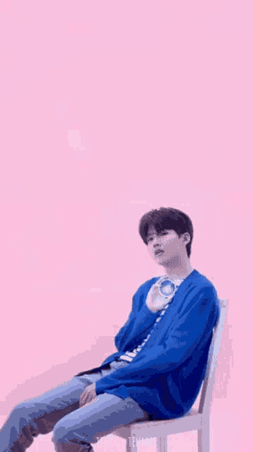 a young man in a blue sweater is sitting in a chair holding a light .