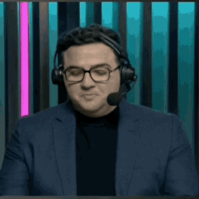 a man wearing glasses and headphones is sitting in front of a pink light .