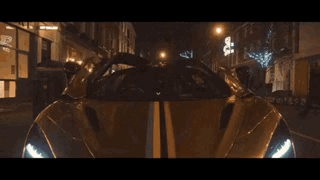 a car is driving down a city street at night .