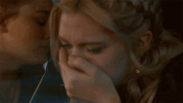 a woman covering her face with her hand in front of another woman