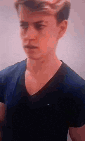 a young man in a blue shirt is looking at the camera .