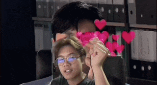 a man wearing glasses is holding a pink heart in front of his face