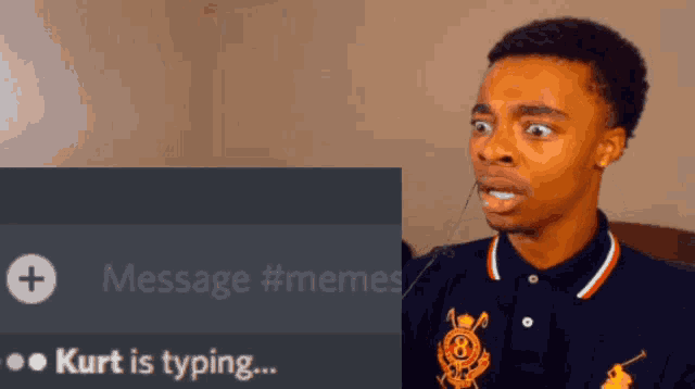 a man in a polo shirt is sitting next to a screen that says kurt is typing