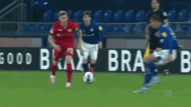 a group of soccer players are playing a game on a field with a sign that says bra on it .