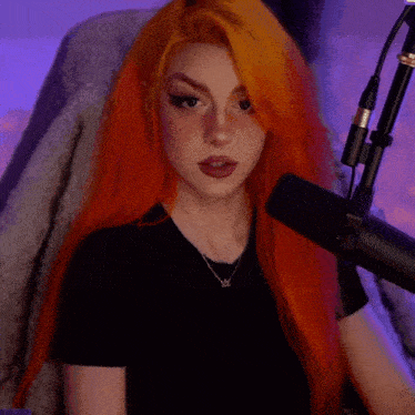 a woman with long red hair is smiling in front of a microphone