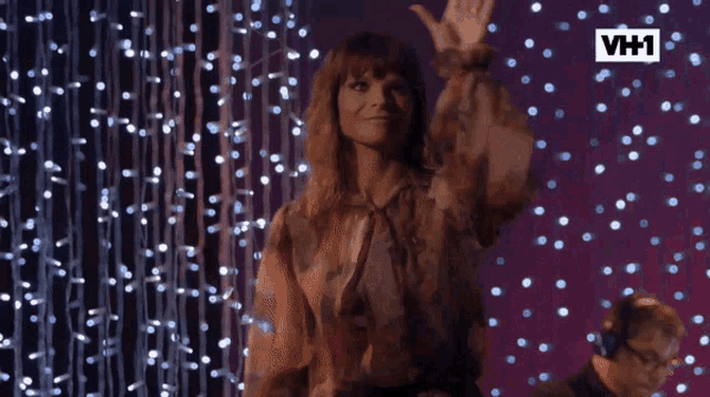 a woman stands in front of a wall of lights and a sign that says vh1