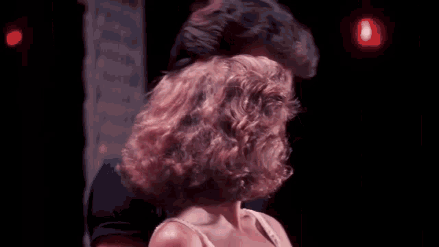 a man and a woman are dancing together in front of a pink wall .