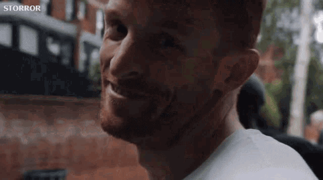 a man with a beard is smiling and looking at the camera in a close up of his face .