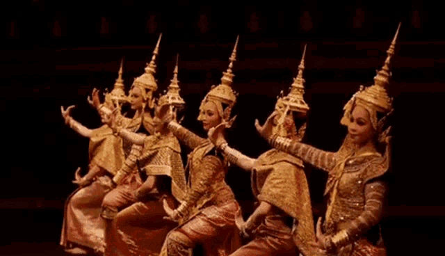 a group of women in traditional costumes are dancing on stage .