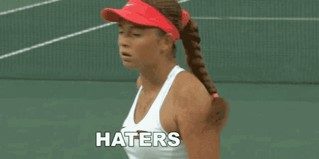 a woman in a red hat is holding a tennis ball and says haters