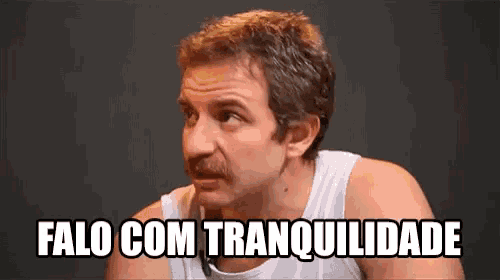a man with a mustache is wearing a white tank top and says " falo com tranquilidade " .