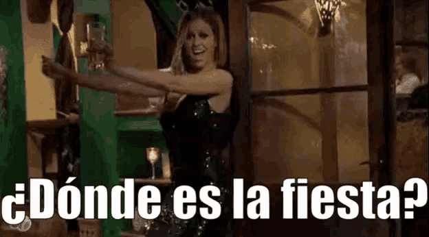 a woman in a black dress is dancing in a room with the words `` donde es la fiesta '' written on the screen .