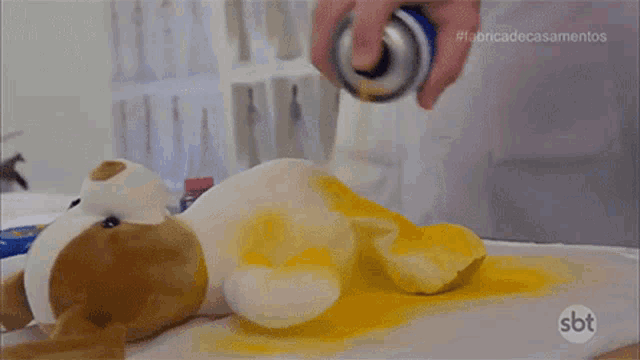 a stuffed animal is being spray painted yellow with a sbt logo on the bottom