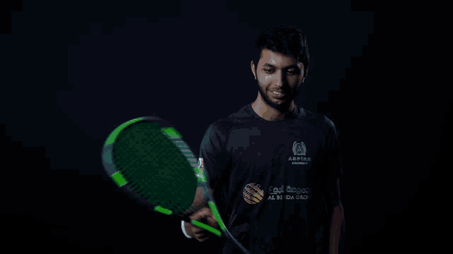 a man wearing a shirt that says aspire on it holds a tennis racquet