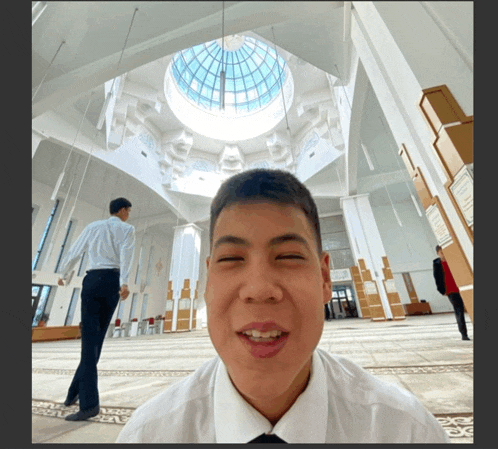 a man in a white shirt and black tie is smiling in front of a dome