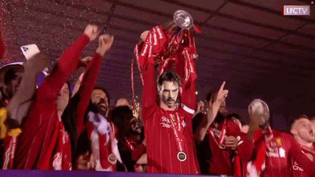 a soccer player holds up a trophy with a picture of a man on his chest