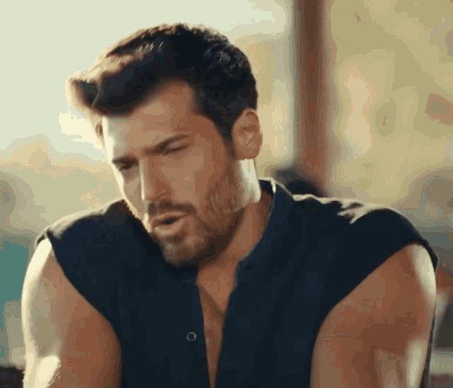 a man with a beard wearing a black shirt without sleeves