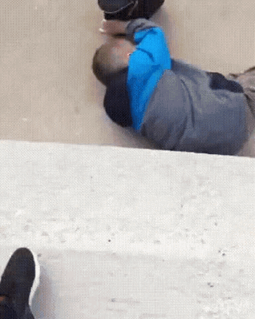 a man in a blue jacket is laying on the ground with his head down .