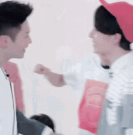a man in a red hat is giving a fist bump to another man .